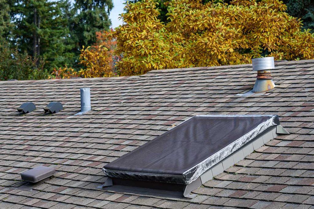 A homeowner compares shingle samples beside an existing roof section in natural daylight.