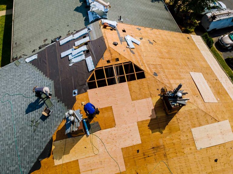 Roof shingles with uneven rows, exposed fasteners, and loose flashing beside a leaking attic ceiling.