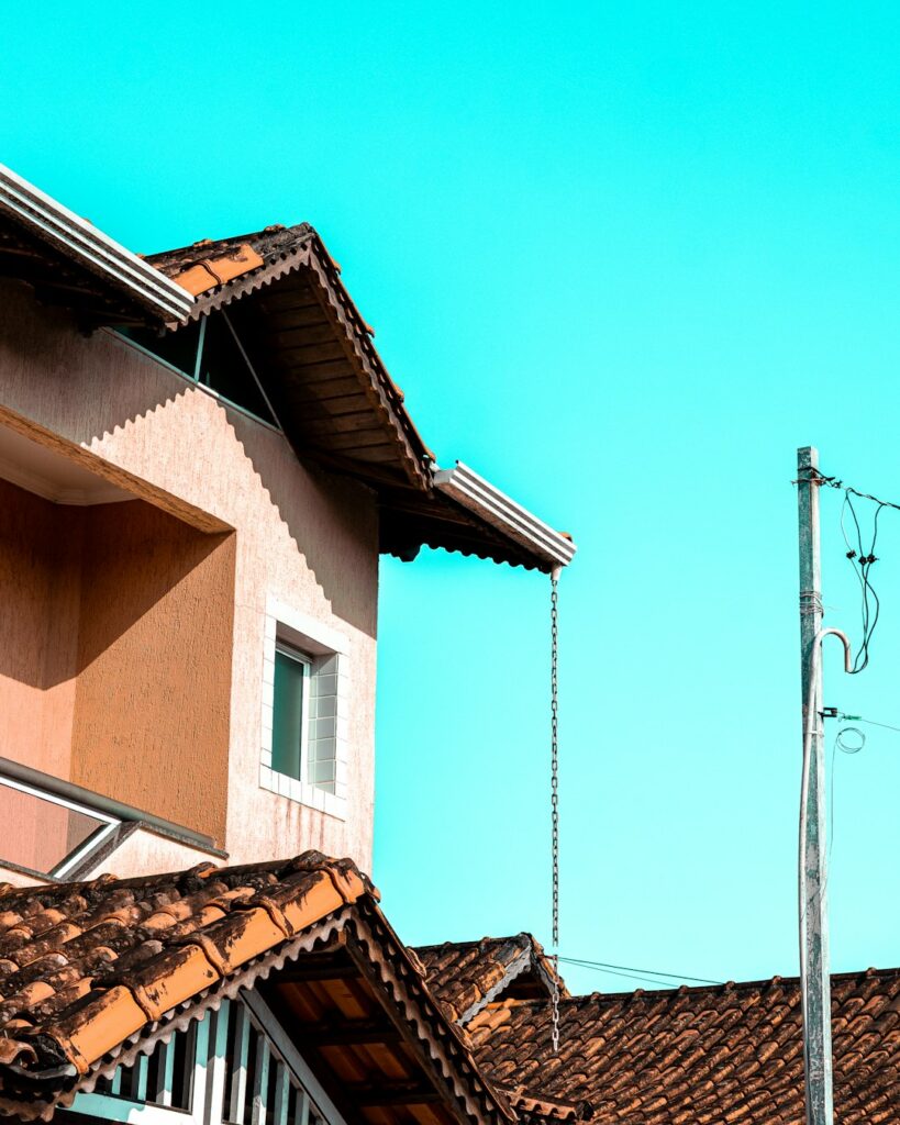 Homeowner inspecting roof edges with binoculars while a ladder, gloves, and maintenance tools rest nearby.